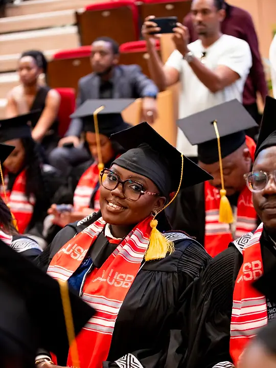 Nyampinga Laetitia seated in her graduation gown, cap and red ALUSB stole